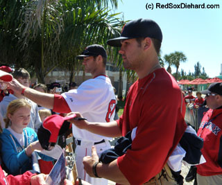 Casey Kelly (in the front, wearing red) and Zach Daeges sign autographs after practice.